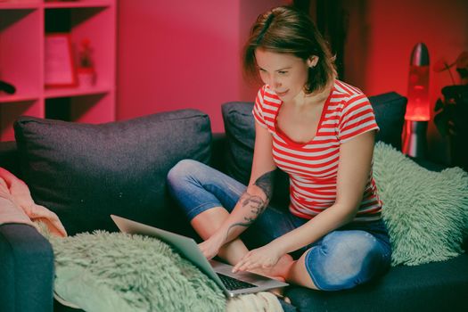 Attractive young Caucasian woman shopping online while entering a credit card number on the laptop computer at home. Inside