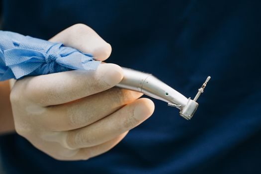 Dentist in sterile latex gloves holding dental tools. Dental instruments in the hands of the doctor. Dentist's hands with gloves working with dental drill in dental office.