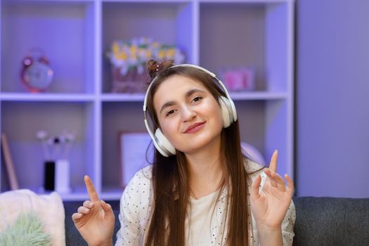 Pretty Young Woman Sitting on Couch While Listening to Music Through Headphone