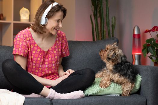 Beautiful young woman listening yo music on smart phone, moving to the rythm while sitting on sofa.