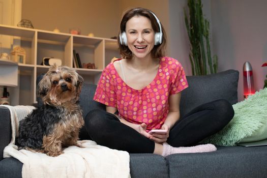 Young woman and her dog with headphone is listening a music
