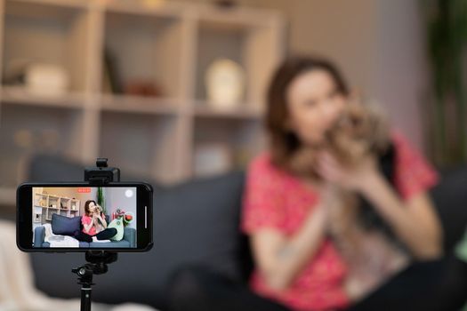 Young woman blogger vlogger influencer sit at home speaking looking at camera talking make video conference call record. Lifestyle blog vlog doing videochat at home concept