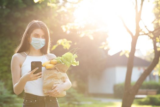 Pandemic. Social distancing. Food delivery. Woman wearing face masks in prevention of coronavirus during quarantine. Woman Using the Mobile Phone.