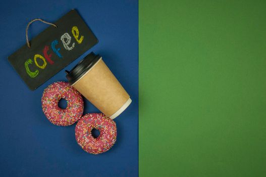 A disposable paper coffee cup with two doughnuts lie on a green and blue background. A place to copy. Top view. Close-up, copy space, background.