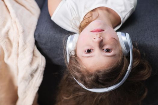 Funny little girl in wireless headphones dancing singing and moving to the rythm. Little girl wearing headphones. Kid in headphones. Happy little girl listening to music with headphones.