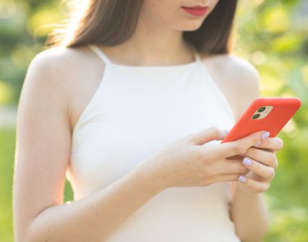 Girl Using Phone Screen Outdoors Hands holding smartphone. Woman Using Smartphone Relaxes on the Bench in Beautiful Green Park. Technology outdoors.