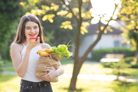 Young girl walking in the Park speaking on Smartphone. Happy girl using a smart phone voice recognition audio ai message speech function on line walking in park.