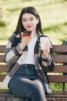 Happy girl using a smart phone voice recognition audio ai message speech function. Woman in trendy casual outfit sits on a bench in the city park
