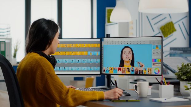 Photo editor working on computer retouching photo with image editing software in creative multimedia company using with stylus pencil. Photographer edits assets in creative media agency office