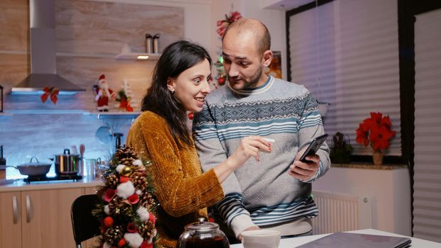 Man and woman using credit card for christmas shopping online on laptop. Festive couple buying presents for family to celebrate seasonal holiday. People purchasing gifts with technology