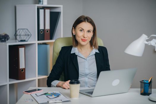 Creative Young Woman while Sitting at Her Workplace Desk. Portrait of the Beautiful Businesswoman While Sitting at Her Desk. Successful and Happy Woman Celebrating Record Sales.