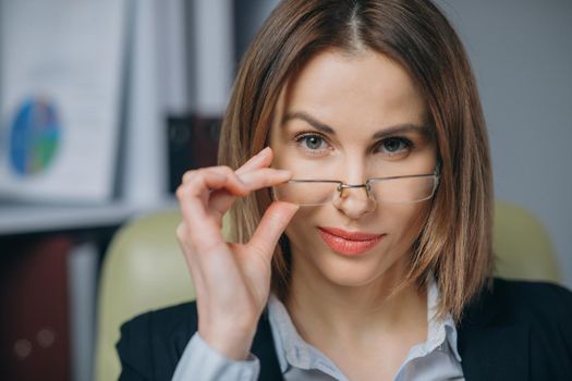 Sexy cute girl holding her glasses and smiling. Beautiful happy businesswoman working at home office.