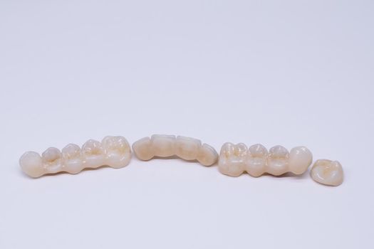 Beautiful ceramic teeth. Porcelain crown and bridge. Dental ceramic bridge in wite background. Metal free ceramic dental crowns