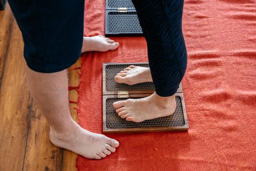 Man helping woman to stand on sadhu yoga board