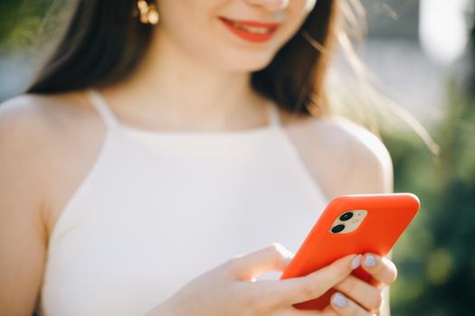 Girl Hands holding smartphone. Woman Using Smartphone in Beautiful Green Park. Technology outdoors.