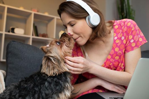 Girl kissing her dog and listening to music at home