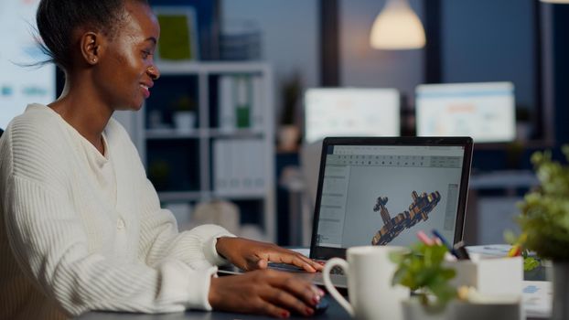 Black woman architect working in modern cad program overtime sitting at desk in start-up business office. Industrial employee studying prototype idea on laptop showing cad software on device display