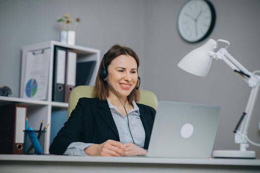 Happy woman in headphones speaking by webcam at webinar training look at laptop, businesswoman talking by video conference call, online teacher teaching consulting client e-coaching concept