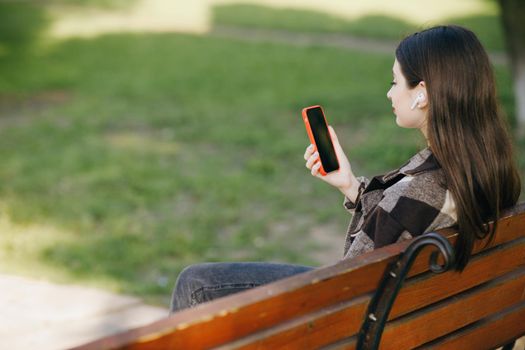 Girl using mobile smart phone in the park. Internet, using smartphone, fashion model, post social network concept.