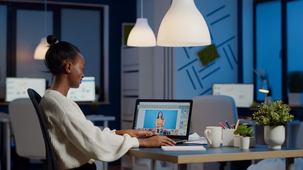 Dark skin freelancer retoucher woman working overtime on laptop with photo editing software. Professional graphic editor retouching photo of a client during night time in home office on performance pc