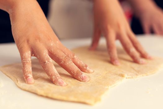 Close up of child doing dough for dessert on christmas day. Happy cheerful joyfull teenage girl helping senior woman preparing sweet cookies to celebrate winter holidays.