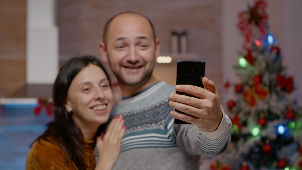 Close up of festive couple talking on video call using smartphone for christmas holiday. People chatting on online conference with family for december celebration. Winter season