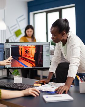 Mixed races of game creators testing the interface of videogame, analysing software problems. Diverse team developing project sitting in startup creative agency company using pc with two monitors