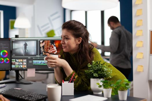 Young sound engineer working on video footage during post production talking with colleague. Content creator editing montage of film using modern software for processing sharing ideas with coworker