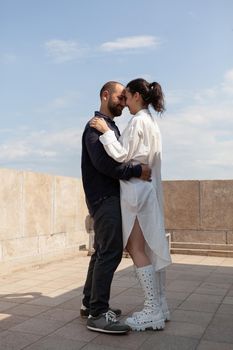 Happy married couple spending relationship anniversary on tower rooftop enjoying hugging during romantic vacantion. Beautiful landscape of metropolitan city. Panoramic view of town buildings