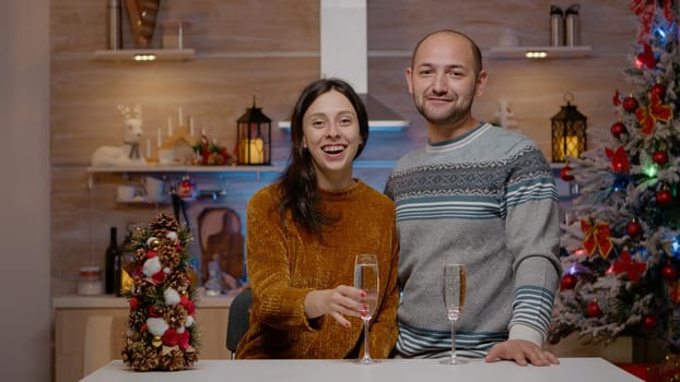 POV of couple using video call and raising glasses of champagne for christmas eve celebration. People on online conference with family drinking alcohol for holiday season festivity