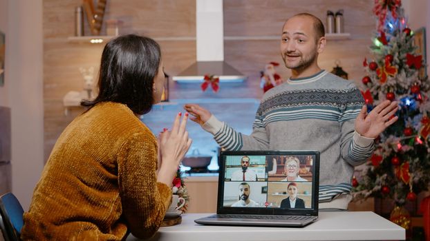 Frustrated man interrupting business video call meeting for woman to celebrate christmas eve together. Person talking to workmates while partner closing laptop for holiday festivity