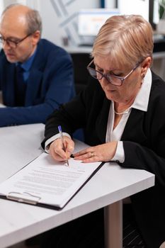 Woman reading financial documents in conference room before signing it. Executive director meeting shareholders in start up office, making satisfactorily agreement.