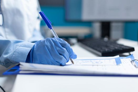 Closeup of african american therapist doctor writing medication prescription on clipboard discussing healthcare treatment with sick patient during consultation. Pysician working in hospital office