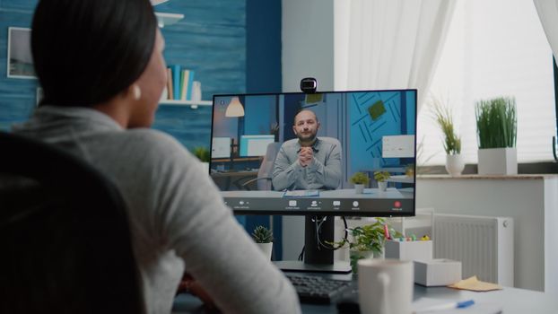 Closeup of student talking with entrepreneur discussing marketing ideas having videocall meeting conference using computer working at desk in living room. Woman using virtual elearning college course