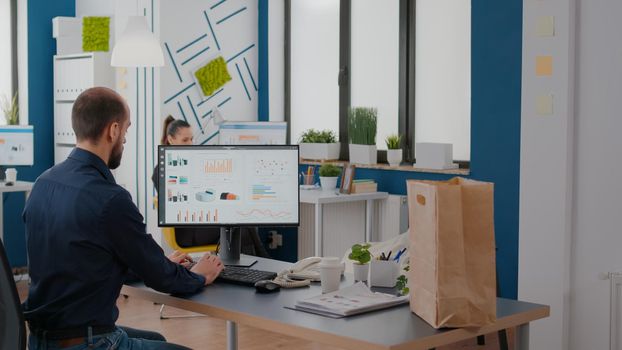 Businessman climbing stairs holding lunch meal paper bag and coffee during takeout lunchtime in company business office working at graphs strategy. Takeaway fastfood order delivered at workplace