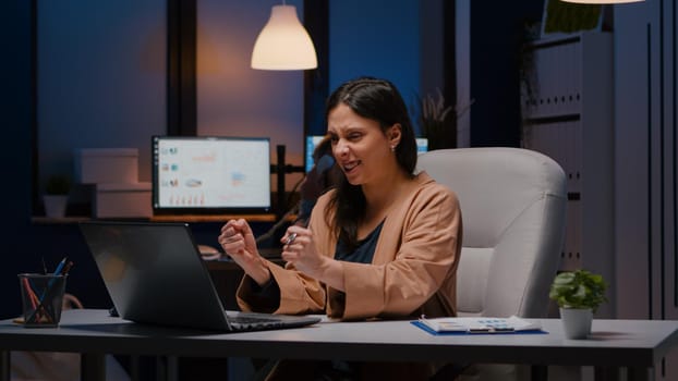 Joyful successful businesswoman enjoying while looking at laptop computer display receiving company good job news. Joyful happy professional entrepreneur working in office late at night