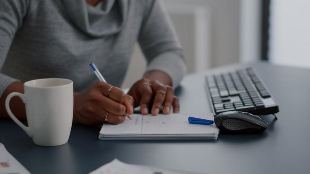 African american student writing high school homework on notebook working remote from home. Black woman studying math using elearning univeristy platform during online courses sitting at desk