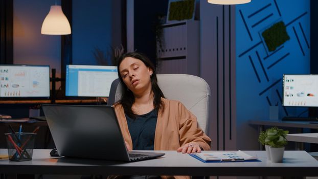 Exhausted entrepreneur woman sleeping in front of laptop while analysing financial statistics in startup company project. Collegue manager waking up and scares her start pllanning economic meeting