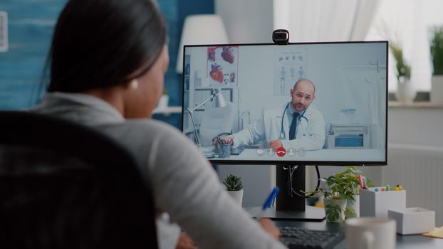 Sick black woman discussing with therapist doctor about sickness diagnosis explaining clinic test result on videocall conference meeting. Student working remote from home during medical appointment