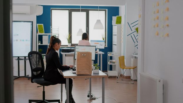 Businesswoman holding takeaway food meal order in takeout lunchtime in business corporate office. Entrepreneur woman sitting at desk table during lunch break working at company statistics