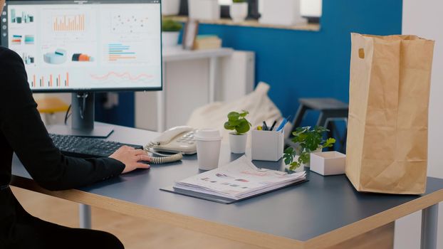 Executive manager carrying paper bag with takeaway food lunch order putting on desk during takeout lunchtime in company office. Delivery man bringing fastfood service packet for businesspeople