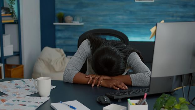 Exhausted tired sleepy student sleeeping on desk table in living room after working at internet job project before deadline. Workaholic disappointed young woman searching online business course