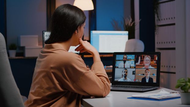 Overworked businesswoman discussing with remote partners on laptop while having online videocall teleconference meeting. Manager talking marketing strategy during company conference in startup office