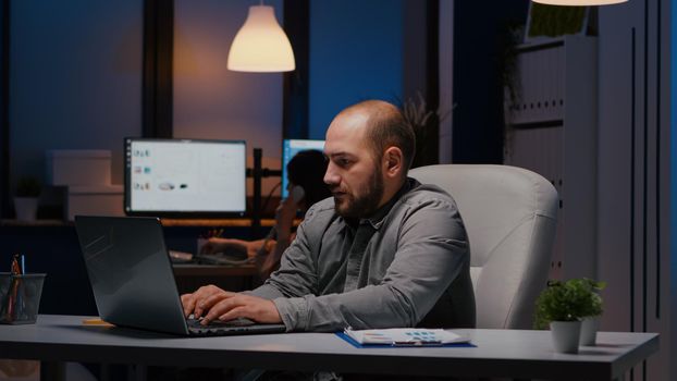 Happy successful businessman enjoying while looking at laptop computer display receiving professional company good job. Joyful happy executive manager working in office late at night