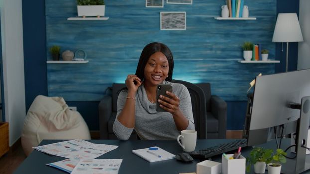 African american student discussing with friend explaining online school lesson during digital videocall telework conference meeting. Woman with dark skin working remote from home sitting at desk