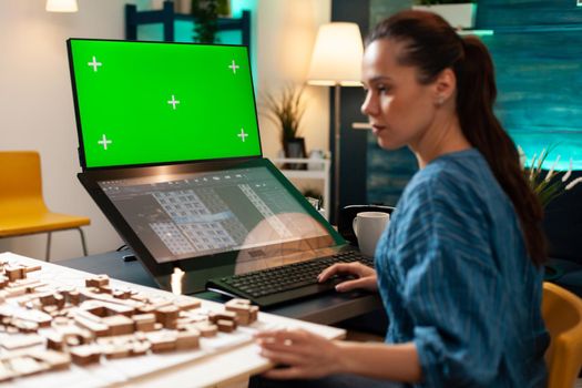 Architecture manager with design plan and green screen on computer monitor using professional equipment and tools. Woman working on blue print with isolated mockup background chroma key