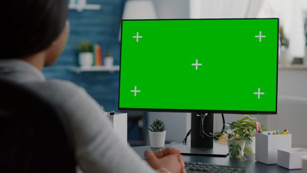 African american student looking at mock up green screen chroma key display listening university professor during online videocall meeting conference. Black woman working remote from home
