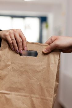 Close up hands of businesswoman in company office taking delivery of fresh food from courier. Employee in business centre recieving restaurant order. Delivery man giving client food order.