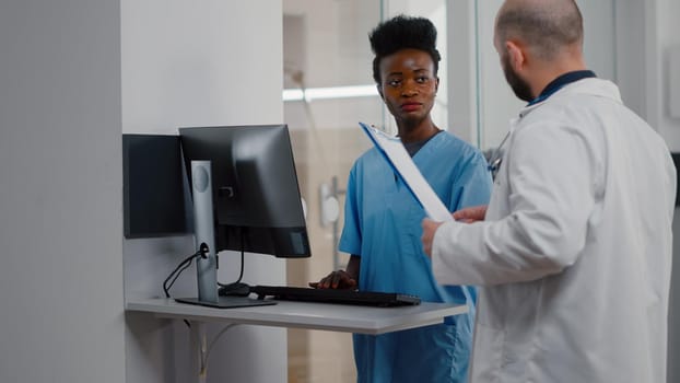 Specialist physician doctor checking sick woman discussing illness treatment while working in hospital ward. Patient sitting in bed explaining symptom disease during recovery appointment