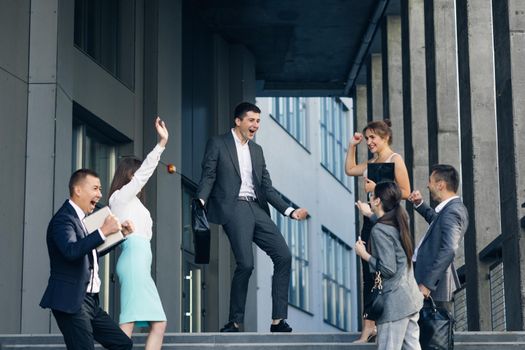 Motivated team leader explaining company development strategy to smiling young diverse colleagues. Happy multiracial business people enjoying working together. Interethnic Group of Business People.